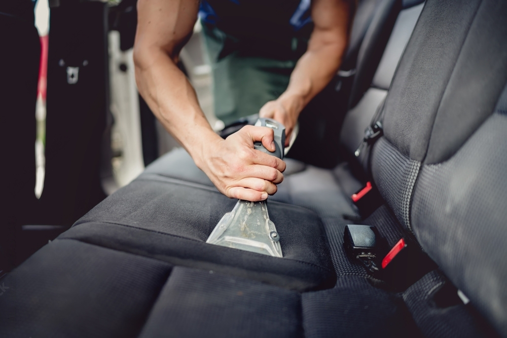 Detailer vacuuming car seat