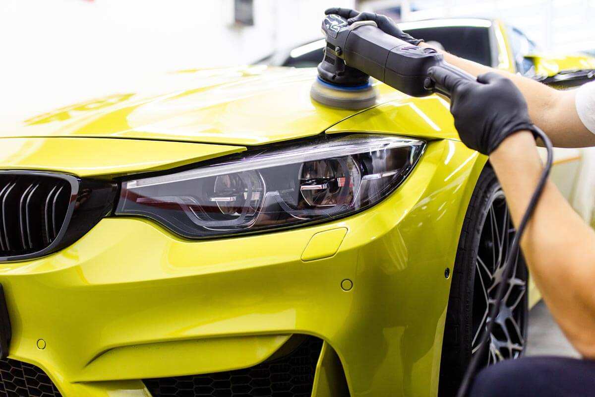 Detailer polishing the hood of a car